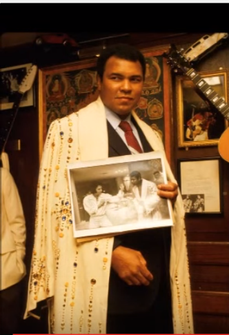 Ali holding photo of him and Elvis with the robe